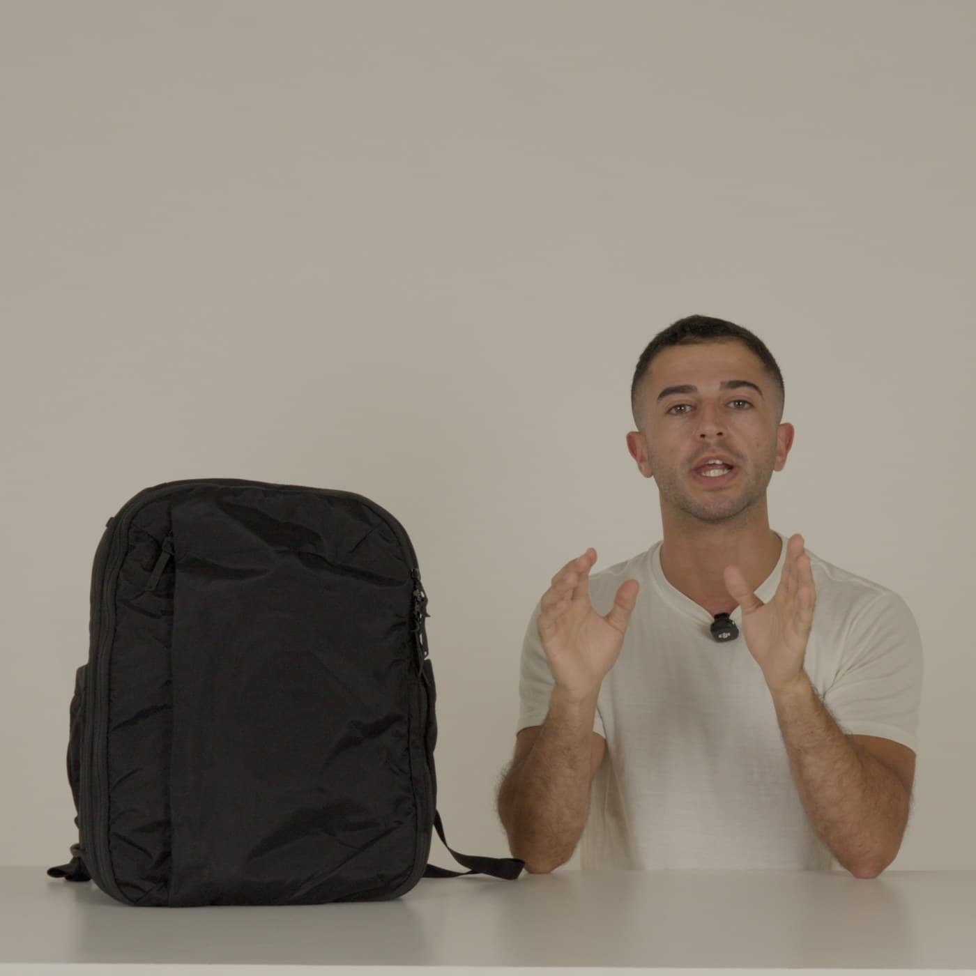 Dylan, the Almond Oak founder, at a white table beside the 25 + 5L Travel Backpack